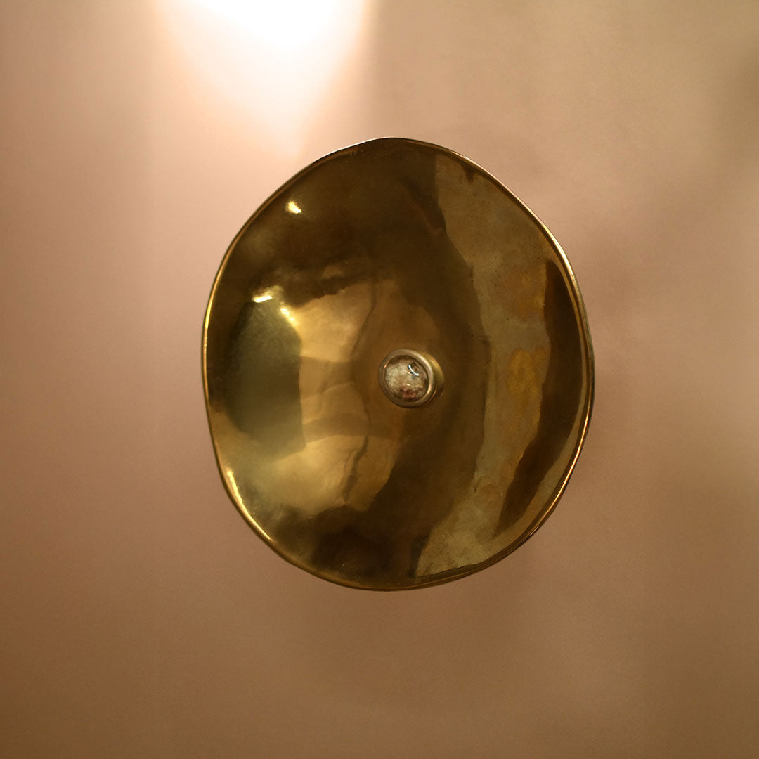 Brass bowl with a white garden quartz in the middle against a beige background