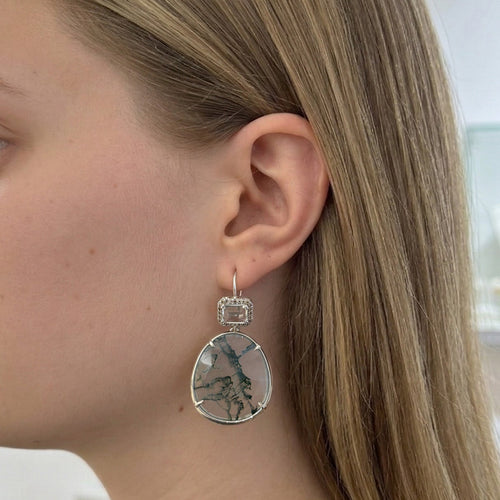 Woman wearing a gold necklace and round earrings in a store setting