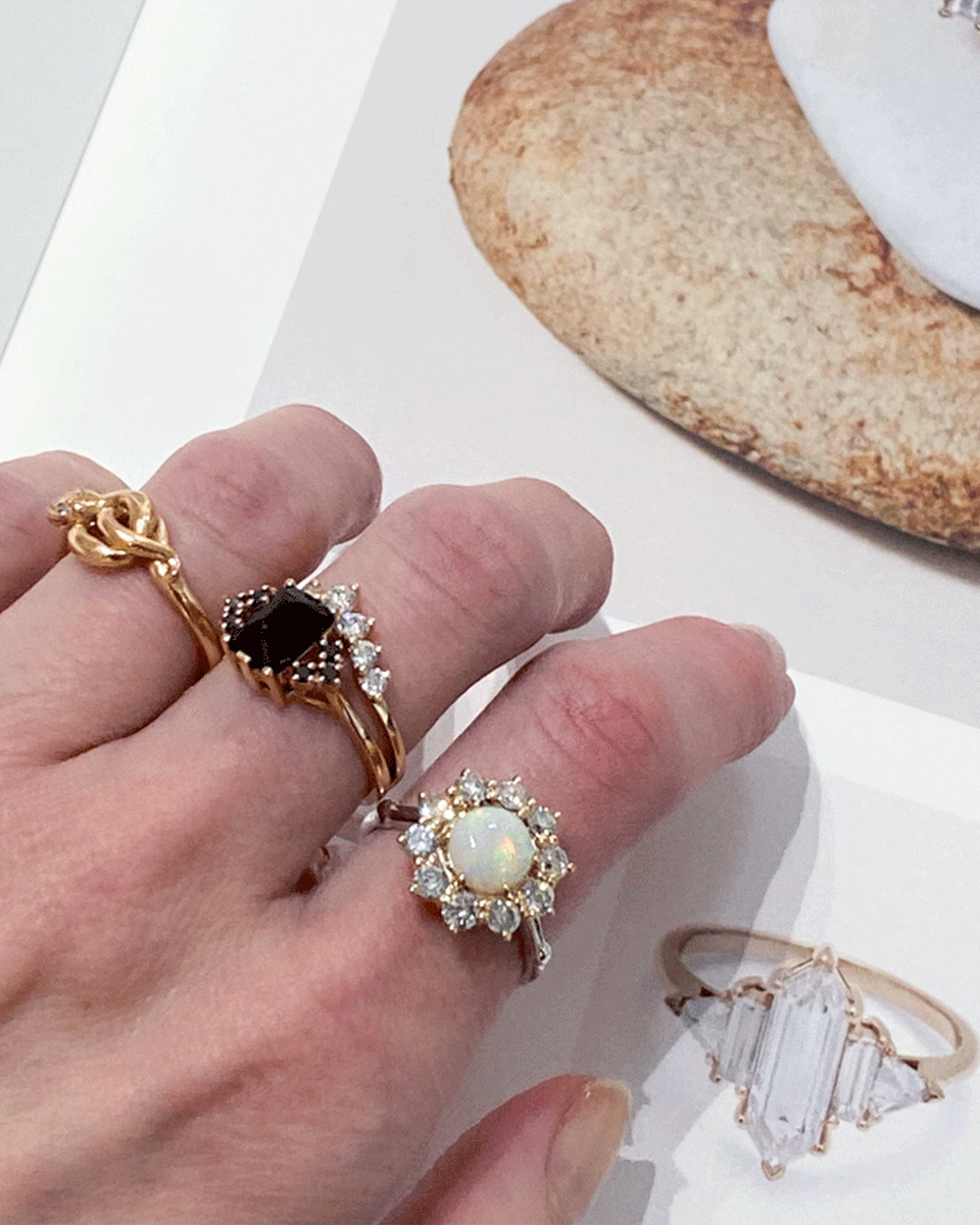 a hand wearing anna sheffield rings on top of a look book at the Anna sheffield jewelry store in new york city.