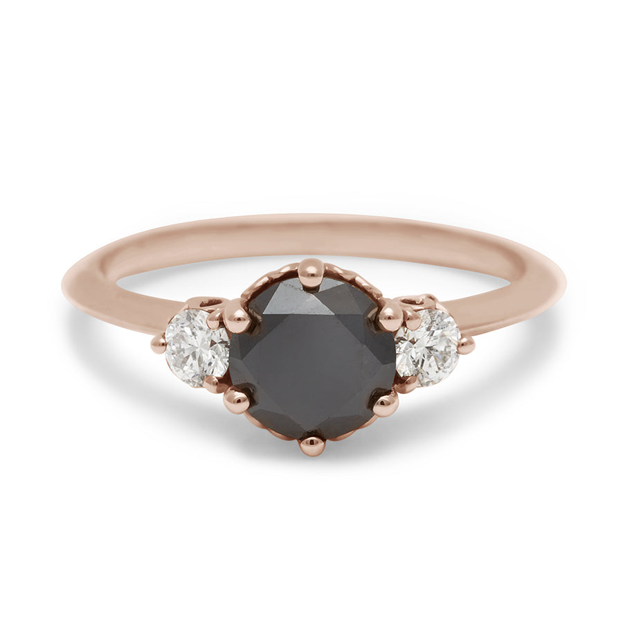 A three stone engagement ring with a round shape black diamond center stone with two white diamond round side stones set in rose gold., Rose Gold