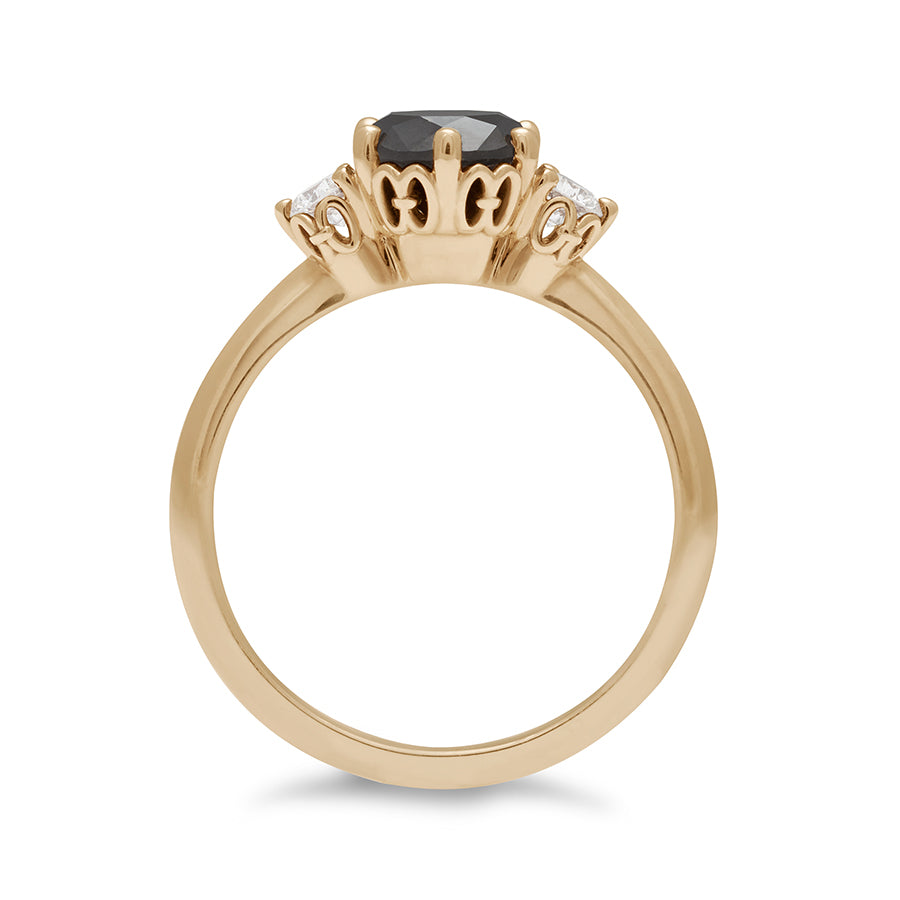 Side view of a three stone engagement ring with a round shape black diamond center stone with two white diamond round side stones set in yellow gold., Yellow Gold
