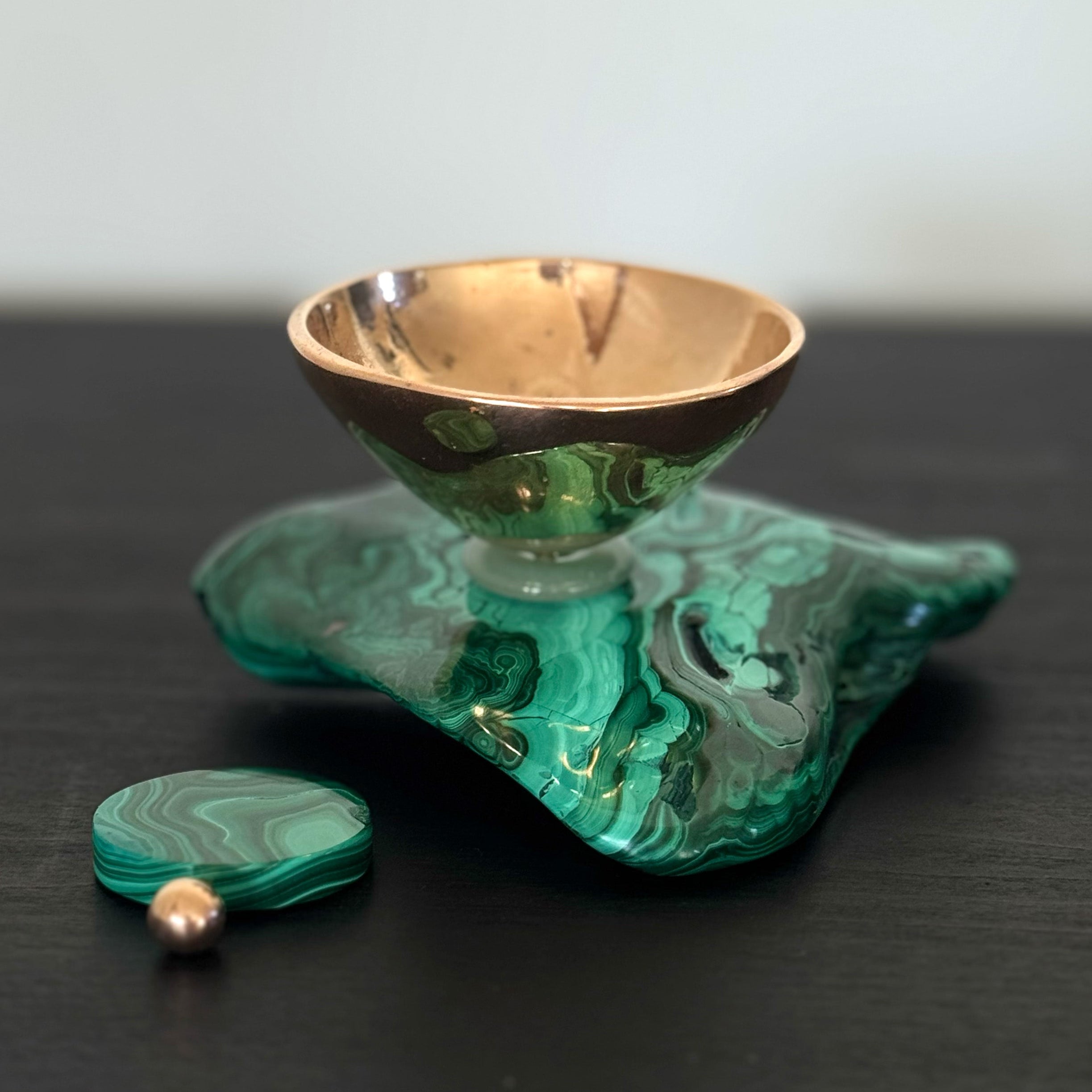 Green and gold decorative item on a dark surface with a white background