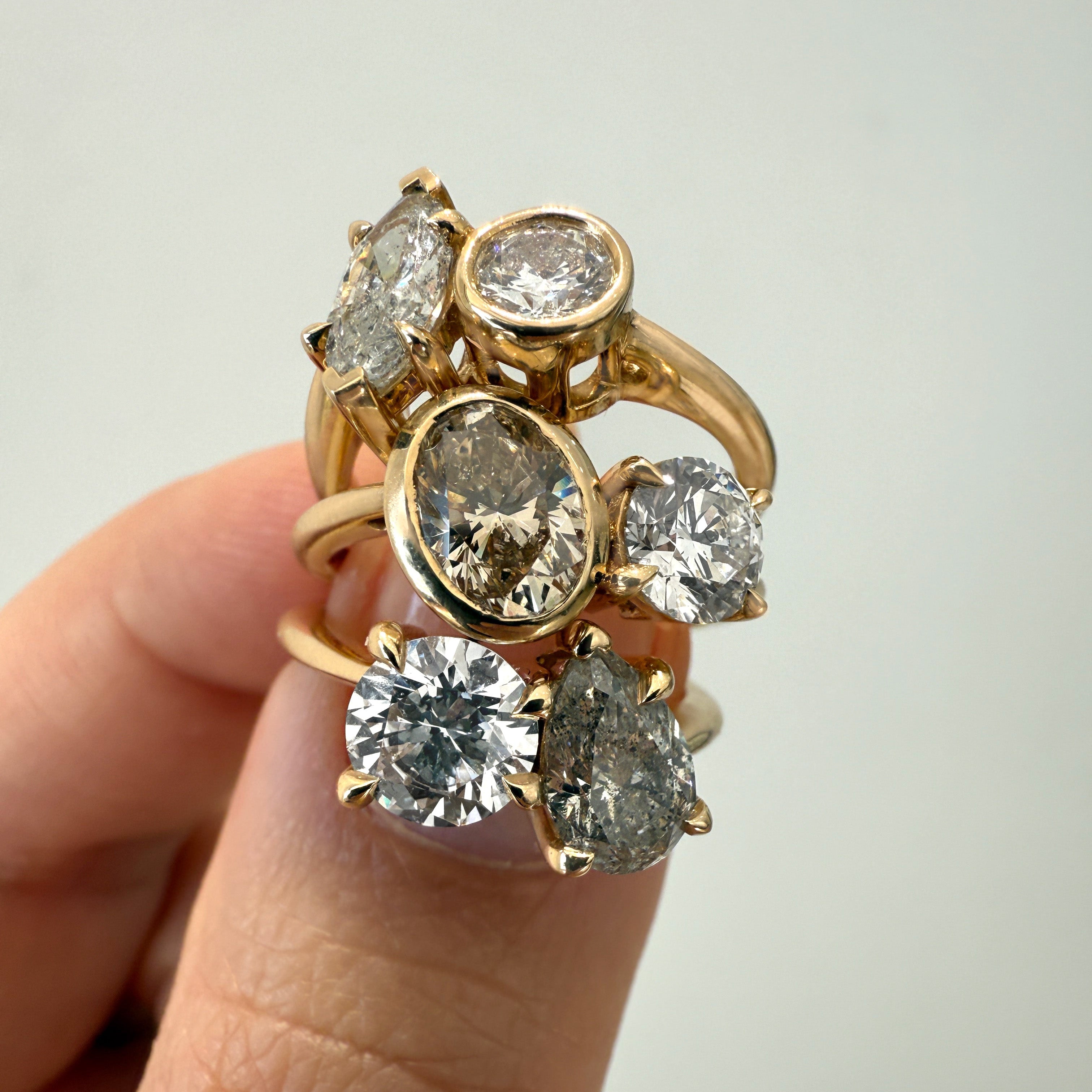 Gold ring with multiple diamonds on a finger against a neutral background