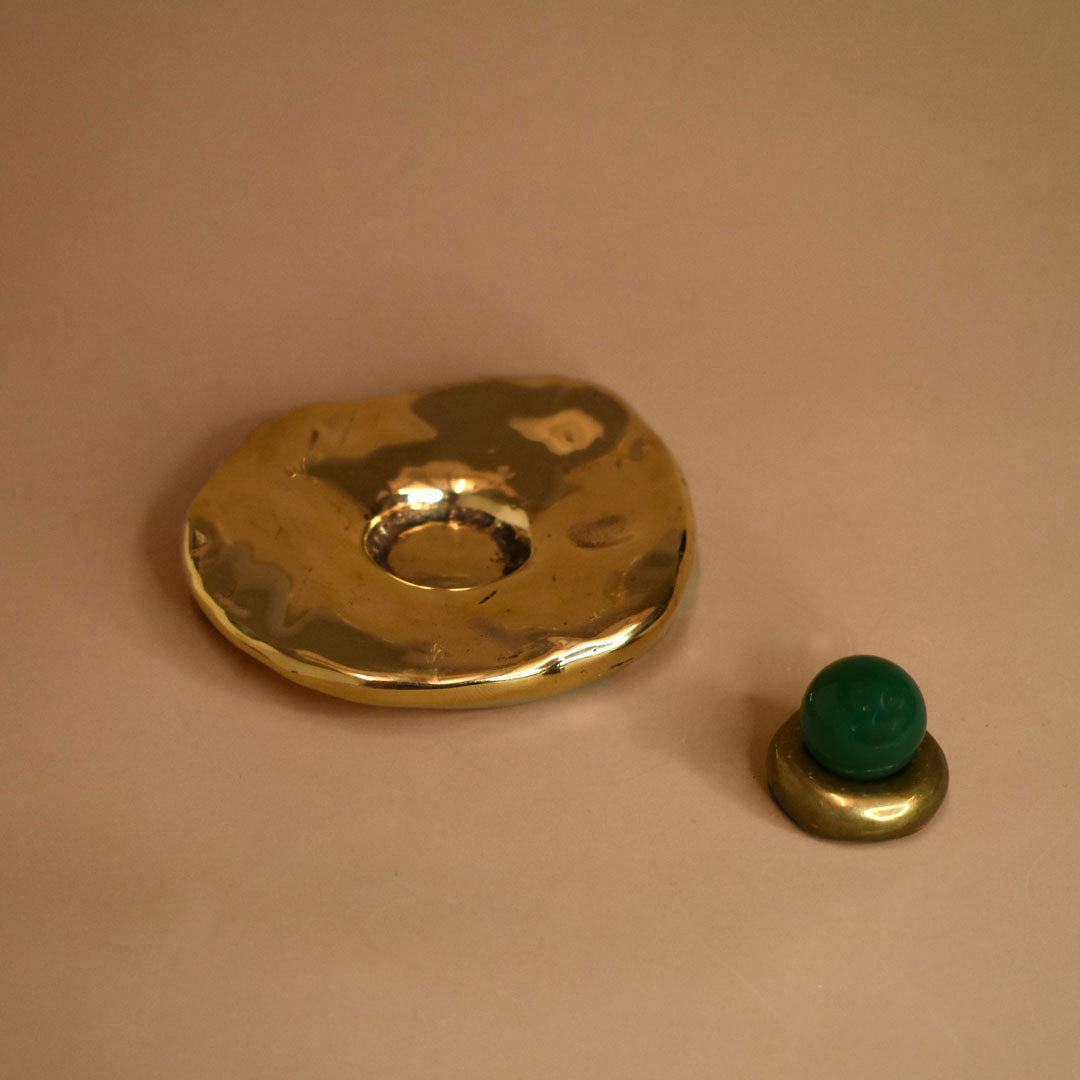 Bronze decorative cone incense burner object with a green onyx gemstone sphere on a bronze ring on a beige background