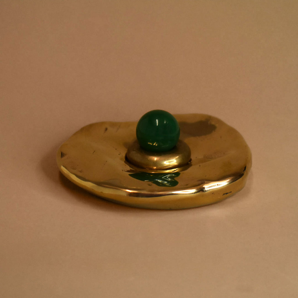 Bronze circular cone incense burner object with a green onyx gemstone sphere on a beige background