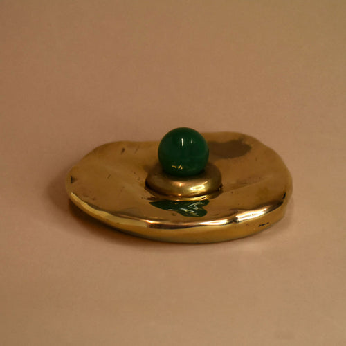 Bronze circular cone incense burner object with a green onyx gemstone sphere on a beige background