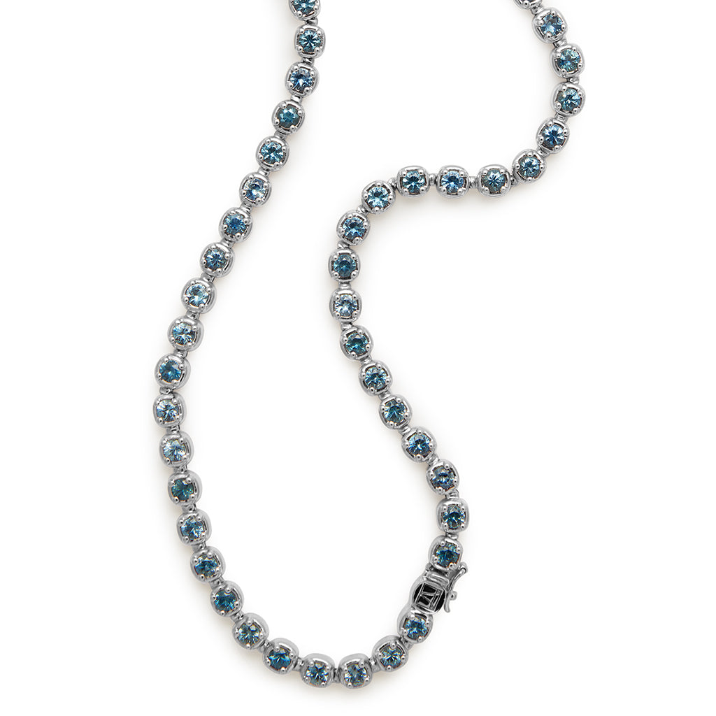 A zoomed in view of a swirled line necklace with Montana sapphires set in eternity in white gold.