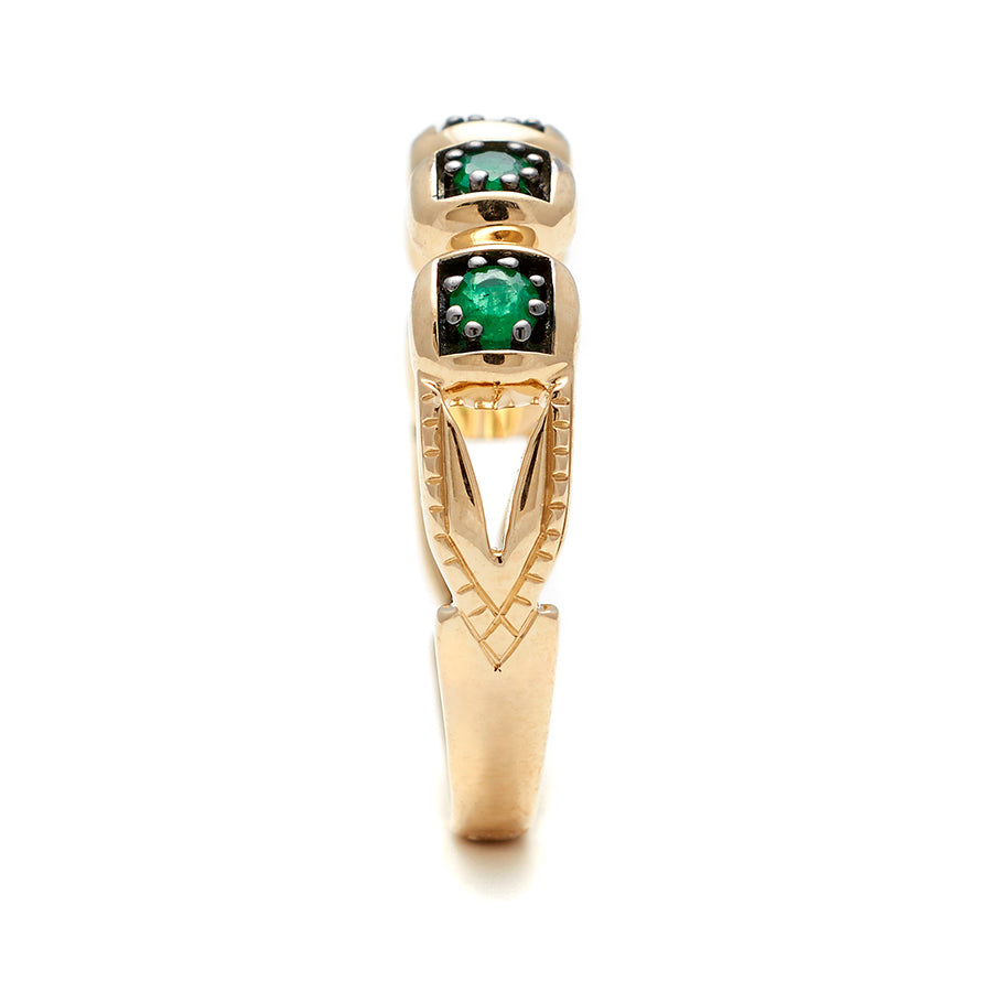 Side view of a band with round emerald stones set in black rhodium and in yellow gold.