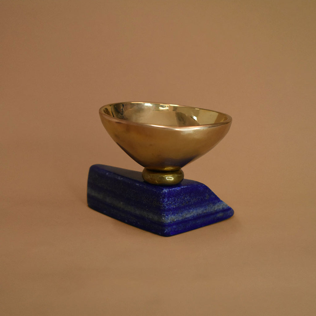 Bronze bowl adhered to a slab of lapis lazuli on a beige background