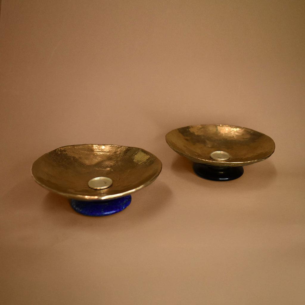 Two bronze dishes, one with lapis lazuli base and one with a black onyx base on a beige background 