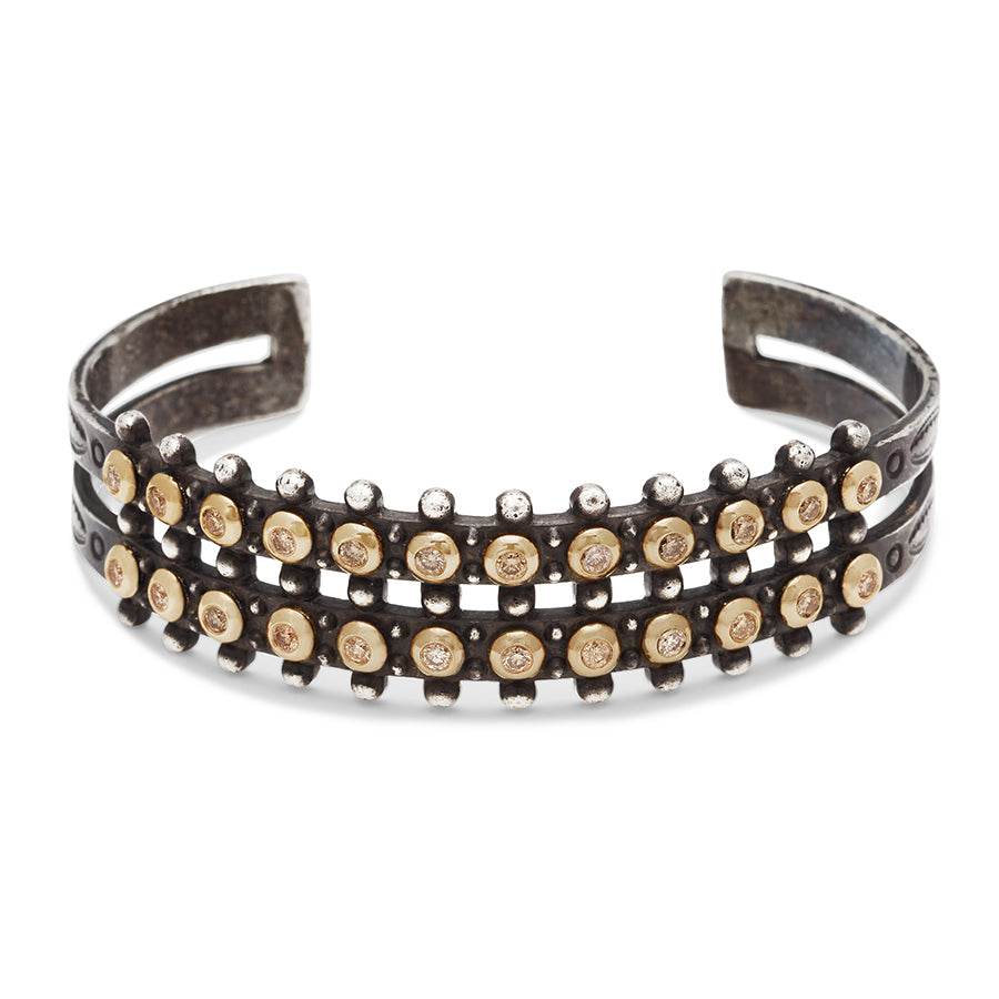 A sterling silver cuff with two rows of champagne diamonds bezel set in yellow gold.
