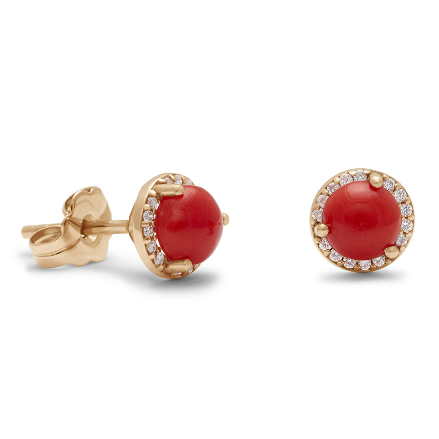 A pair of medium coral center stone earrings with a halo of white diamond set in yellow gold one earring angled.