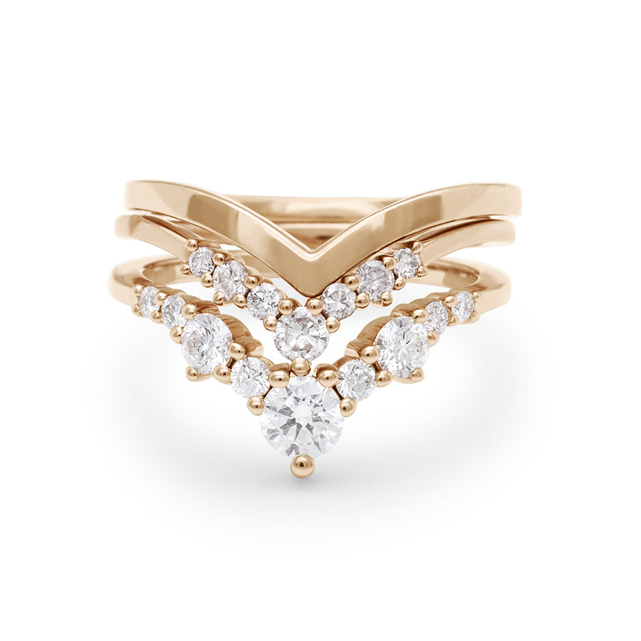 Two chevron shaped white diamond nesting bands set in yellow gold with a solid chevron band stacked on top.