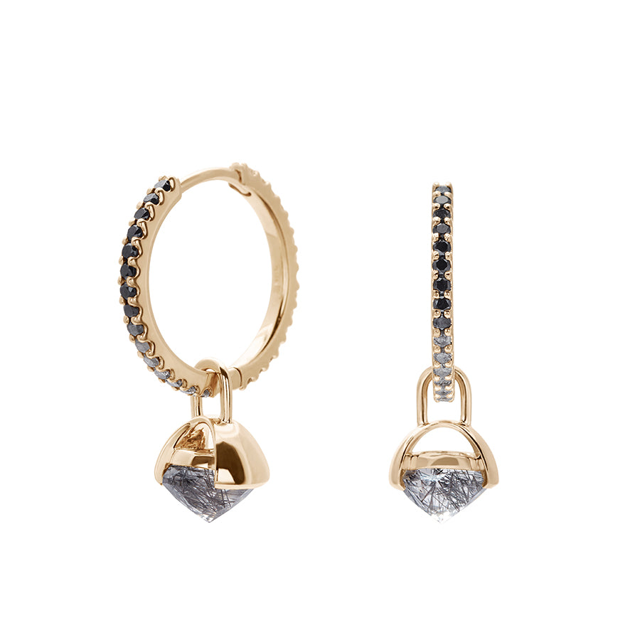 A pair of eternity hoops with ombre of black to grey to white diamonds with a black rutilated quartz droplet set in yellow gold one earring angled.