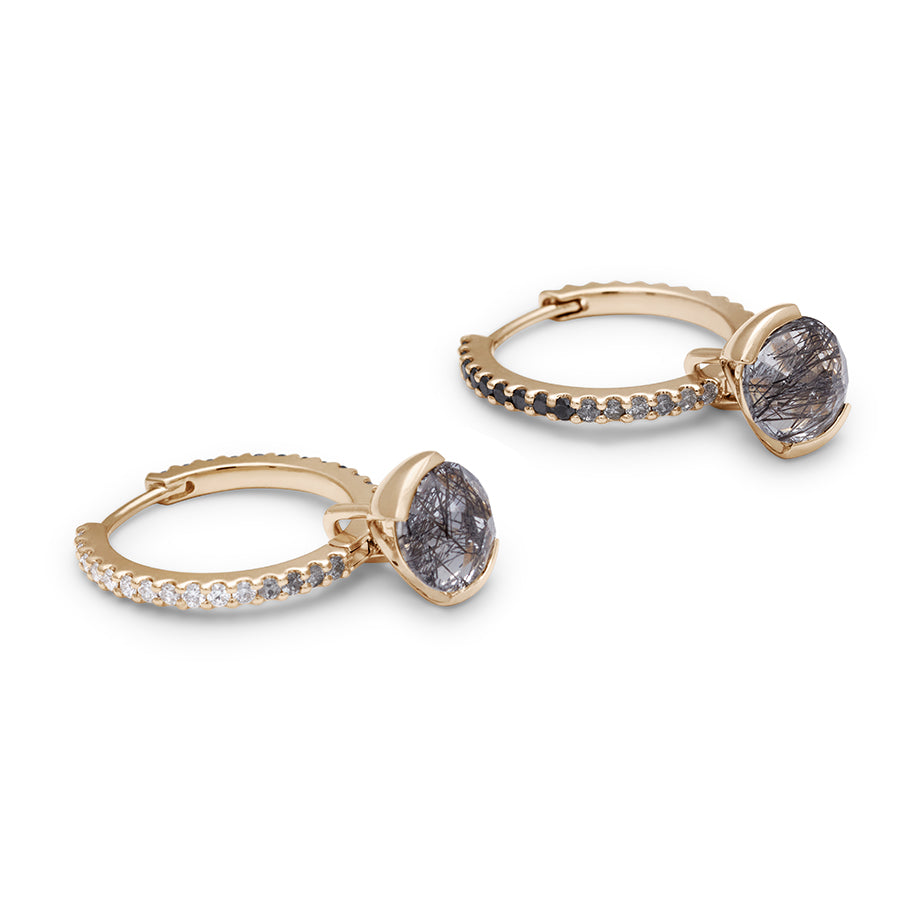 Side view of a pair of eternity hoops with ombre of black to grey to white diamonds with a black rutilated quartz droplet set in yellow gold.