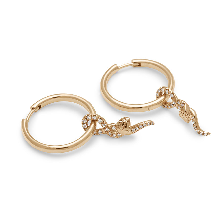 Side view of a pair of hoop earrings with a serpent charm at the bottom with white diamond pave set in yellow gold.