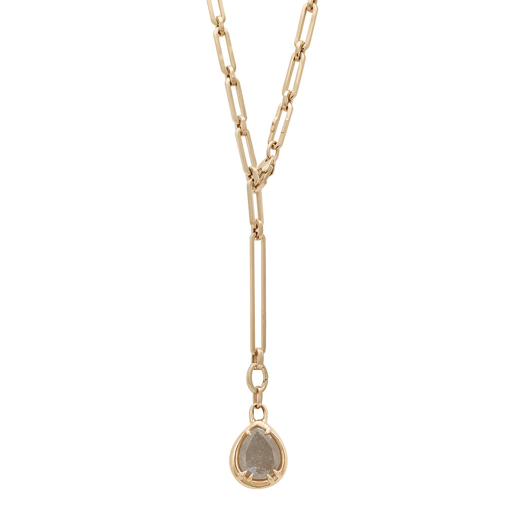 A zoomed out view of a grey diamond charm in a bezel setting with claw prongs set in yellow gold on a mixed link yellow gold chain.