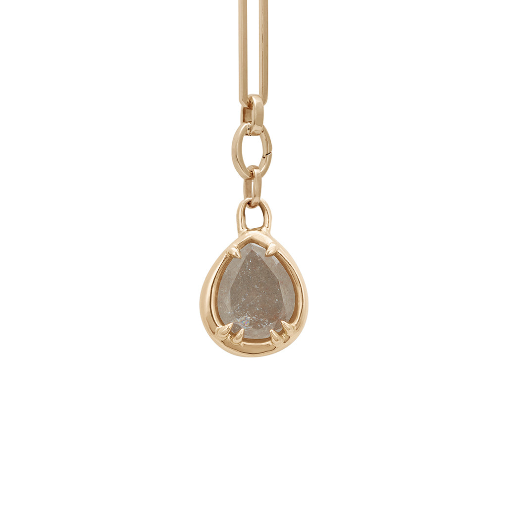 A zoomed in view of a grey diamond charm in a bezel setting with claw prongs set in yellow gold on a mixed link yellow gold chain.