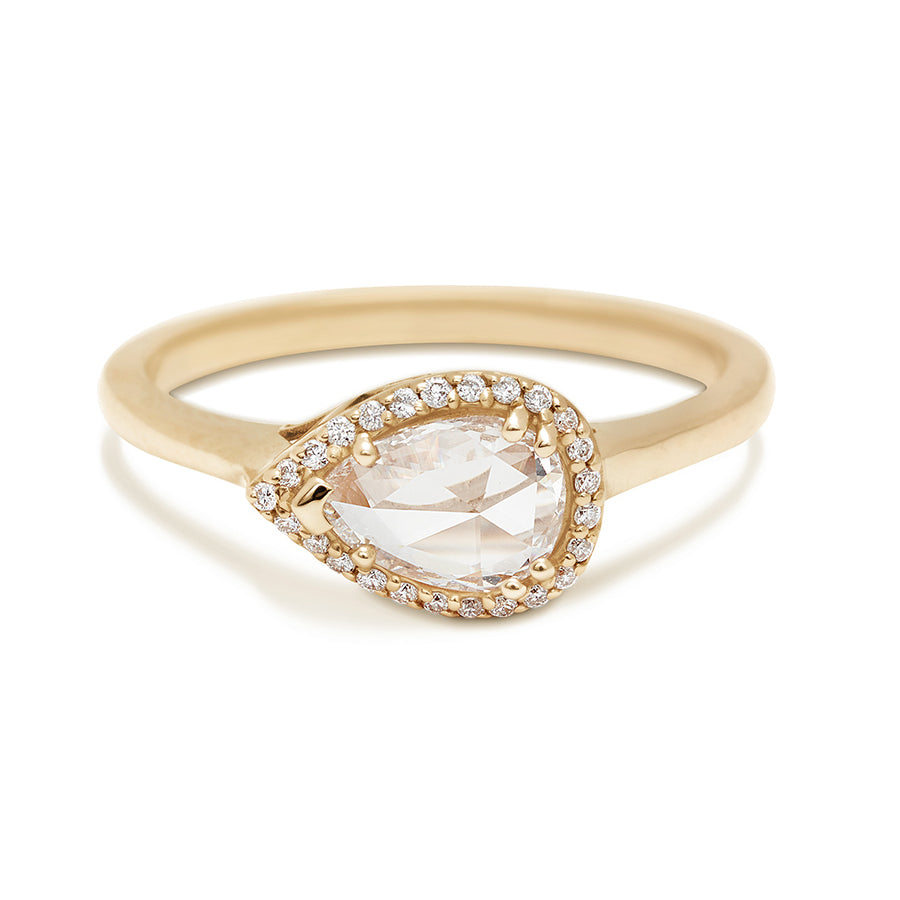 A pear shaped ring with a white diamond and white diamond halo set in yellow gold.