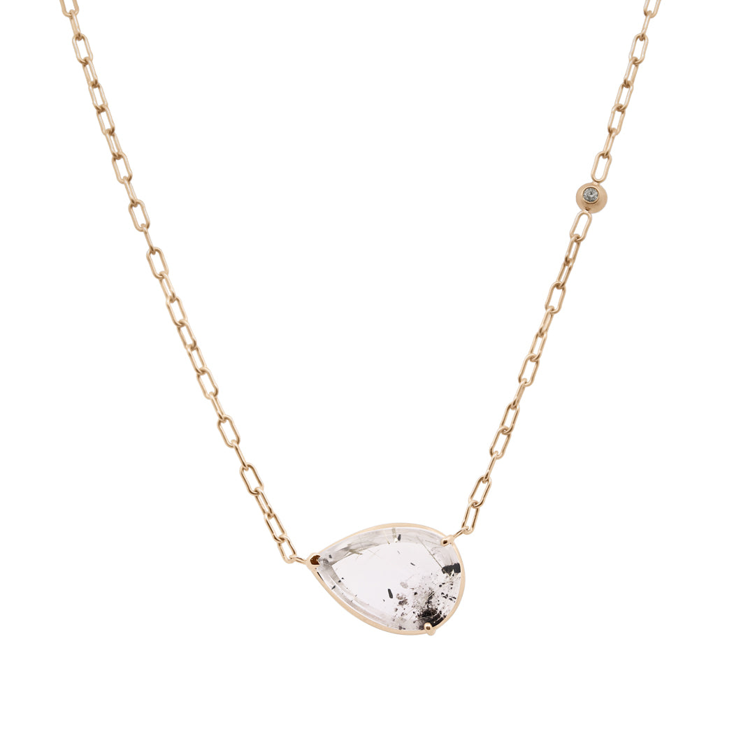 Gold necklace with a teardrop-shaped clear gemstone on a white background