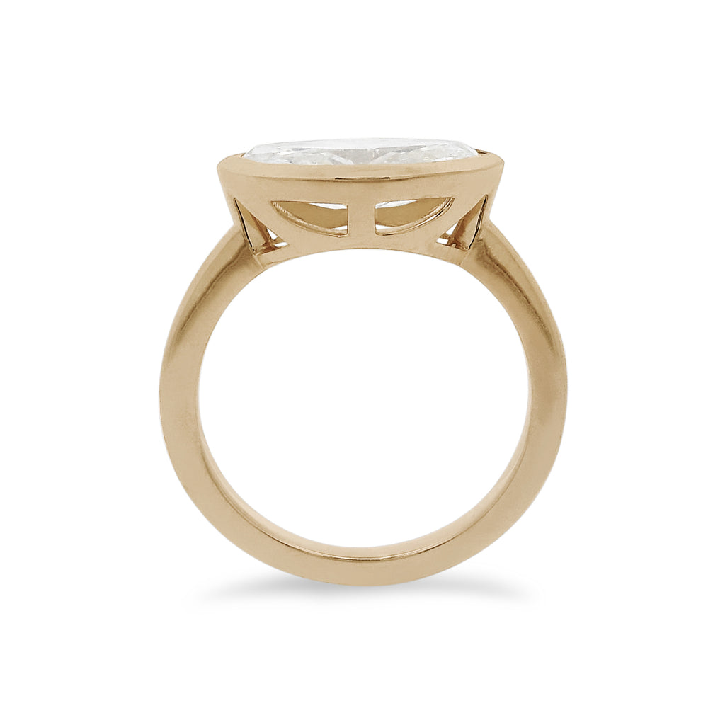 A white moval cut diamond set east west in a yellow gold bezel setting. 