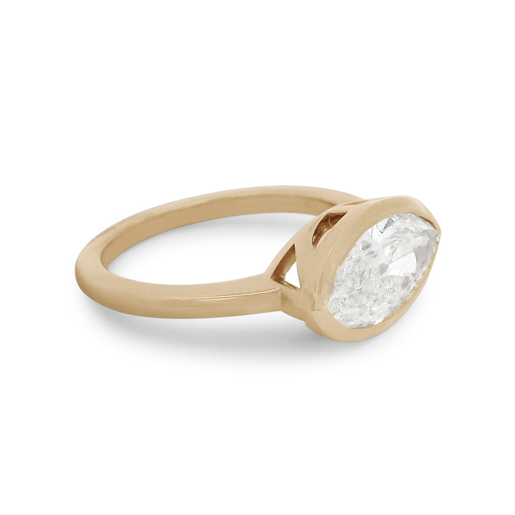 A white moval cut diamond set east west in a yellow gold bezel setting. 