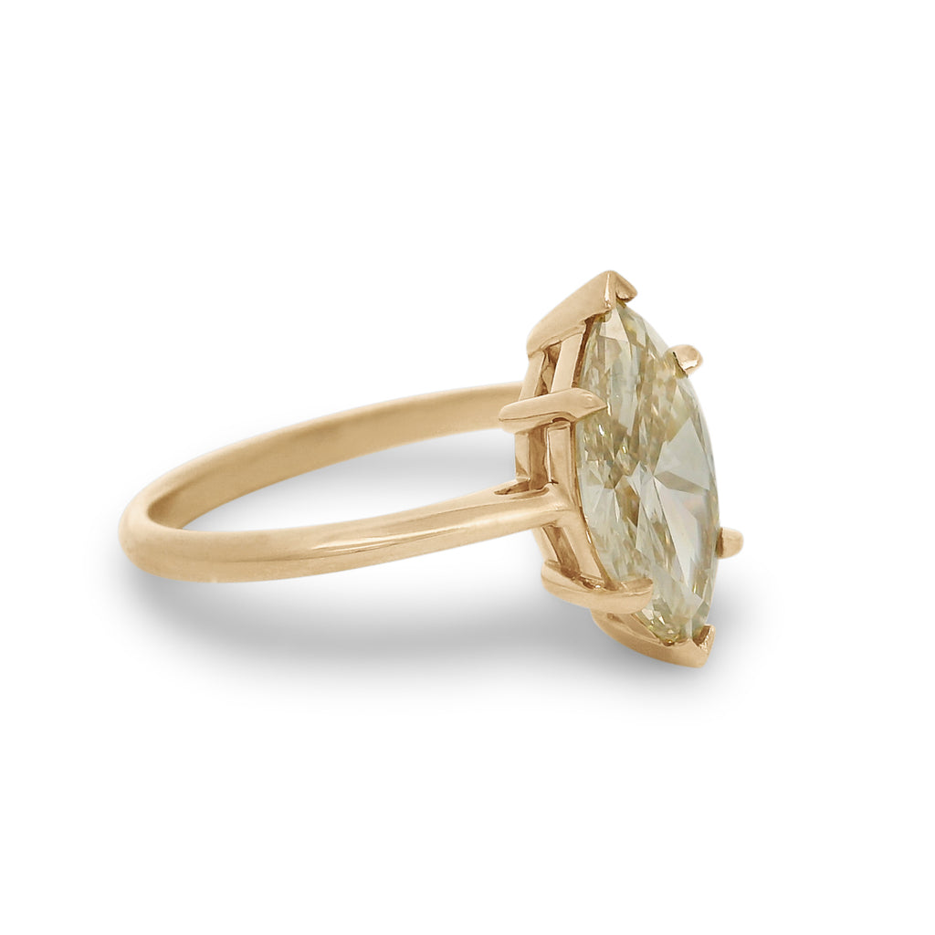 A champagne marquise cut diamond solitaire ring set in yellow gold on a white background