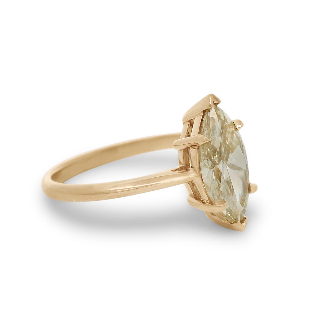A champagne marquise cut diamond solitaire ring set in yellow gold on a white background