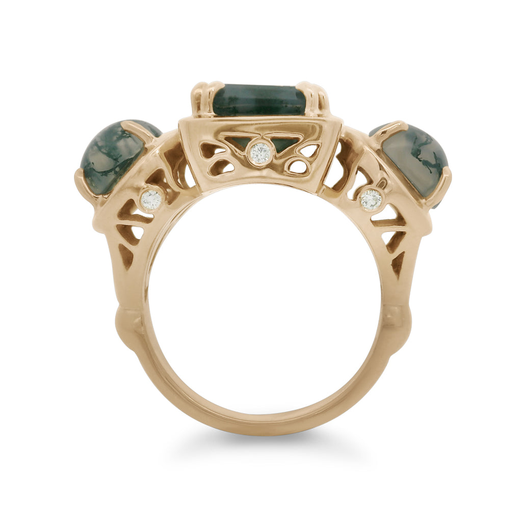 Gold ring with green gemstones and white diamond details on a white background