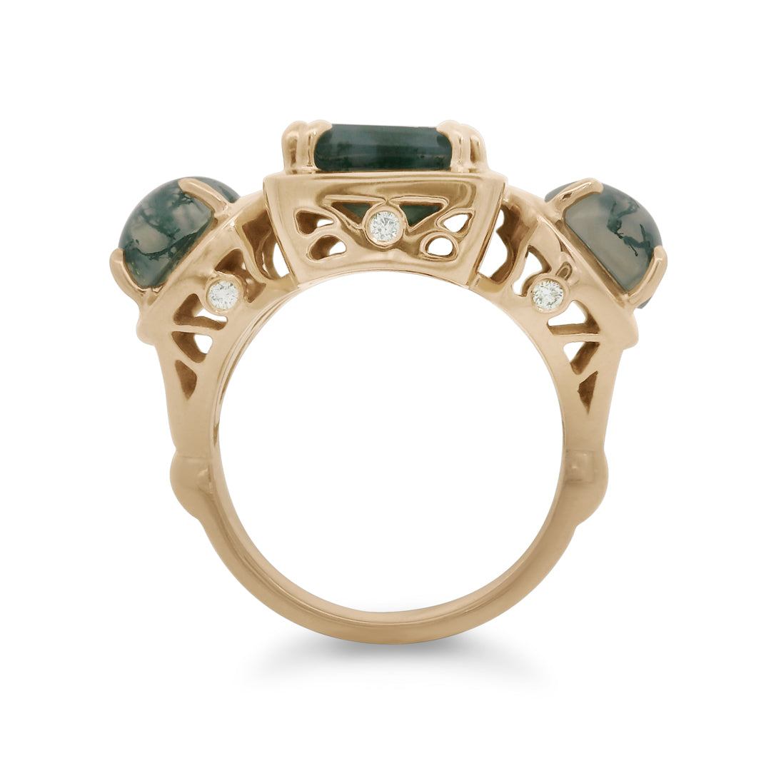 Gold ring with green gemstones and white diamond details on a white background