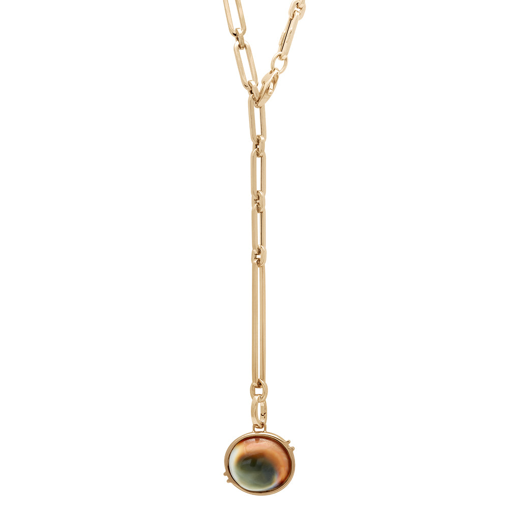A zoomed out view of a shiva stone charm in a bezel setting set in yellow gold on a mixed link yellow gold chain.