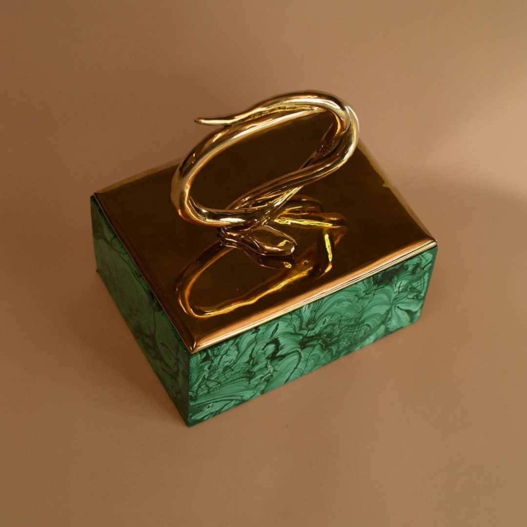 A malachite box with a bronze lid featuring a snake design on a beige background