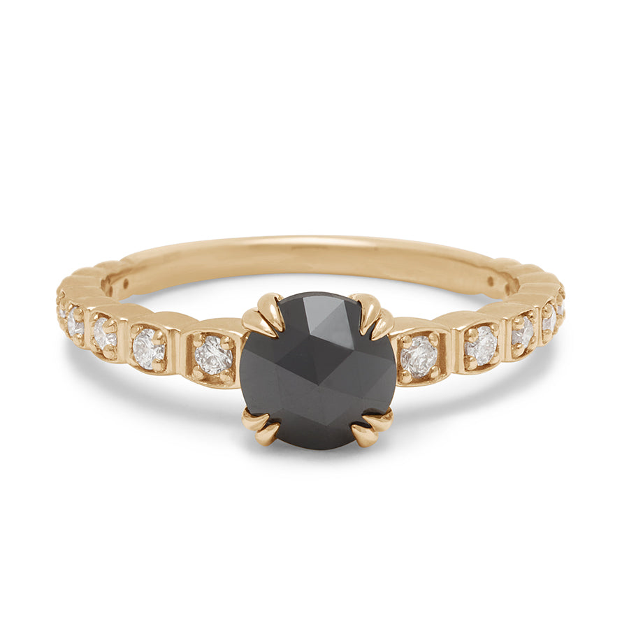 A solitaire ring with a round black diamond with white diamond pave around the band set in yellow gold.