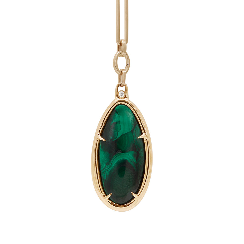 A zoomed in view of a malachite charm in a bezel setting with claw prongs set in yellow gold with white diamond accent stone on a mixed link yellow gold chain.