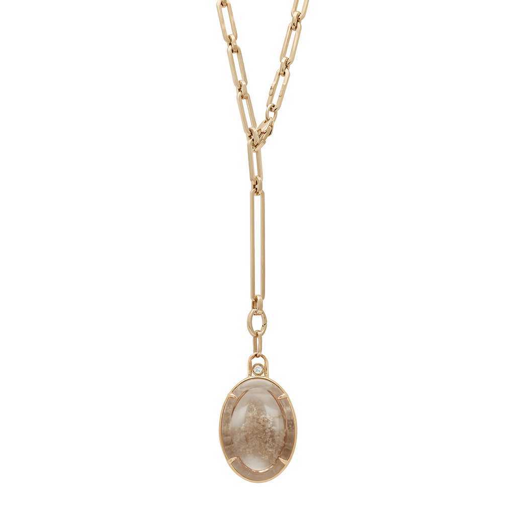 A zoomed out view of a quartz charm in a bezel setting with claw prongs set in yellow gold with white diamond accent stone on a mixed link yellow gold chain.