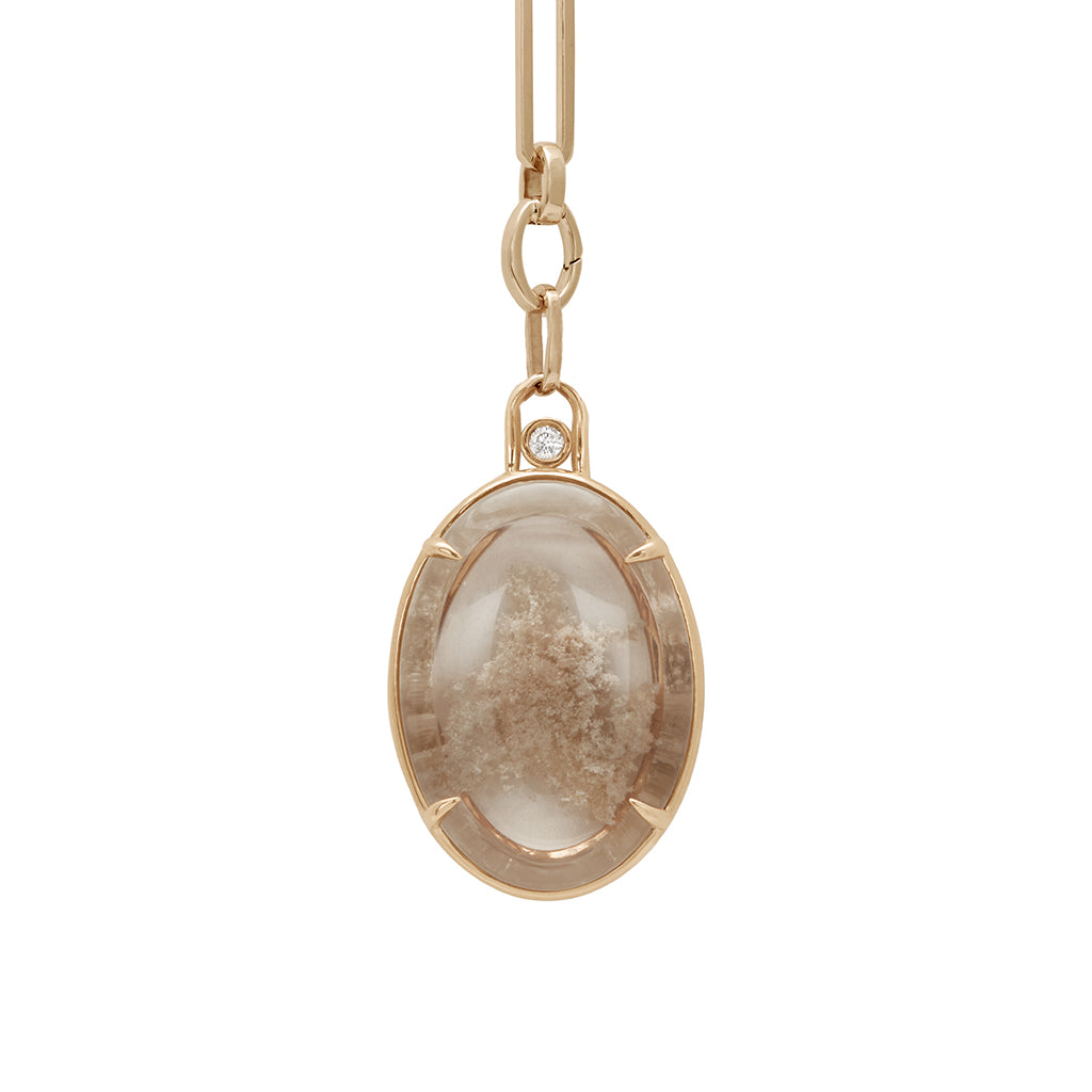 A zoomed in view of a quartz charm in a bezel setting with claw prongs set in yellow gold with white diamond accent stone on a mixed link yellow gold chain.