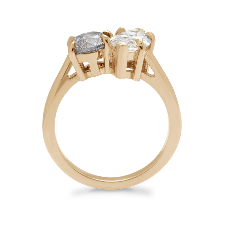 Side view of a two diamond ring with a marquise white diamond set next to a round grey diamond set in yellow gold.