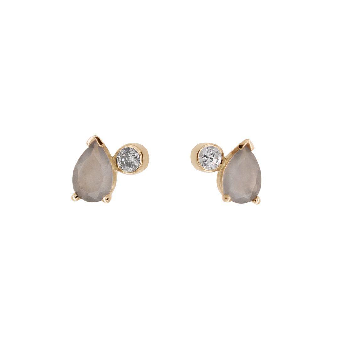 A pair of stud earrings featuring pear shaped grey moonstones and round grey diamonds set in yellow gold on a white background.