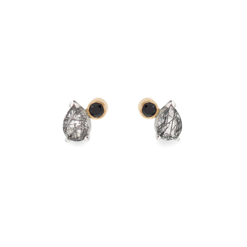 A pair of stud earrings featuring pear shaped black rutile quartz and round black diamonds set in yellow gold and sterling silver on a white background.