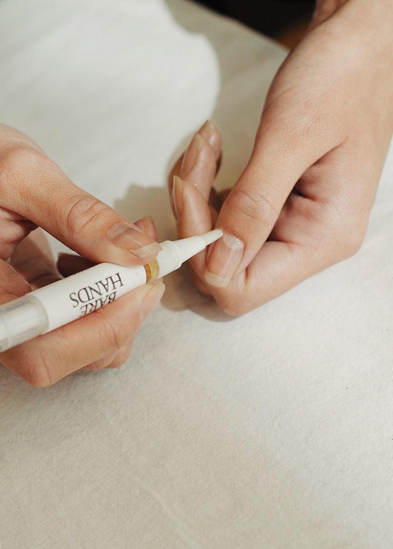 Person applying a small tube of cream to their finger on a light background