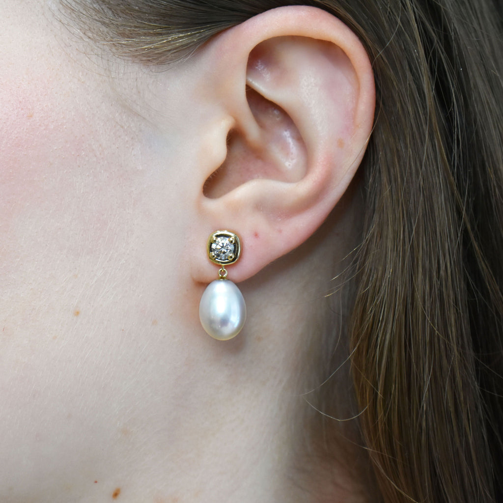 A drop earring with a .36ct round champagne diamond and fresh water pearl. Set in 14k yellow gold.