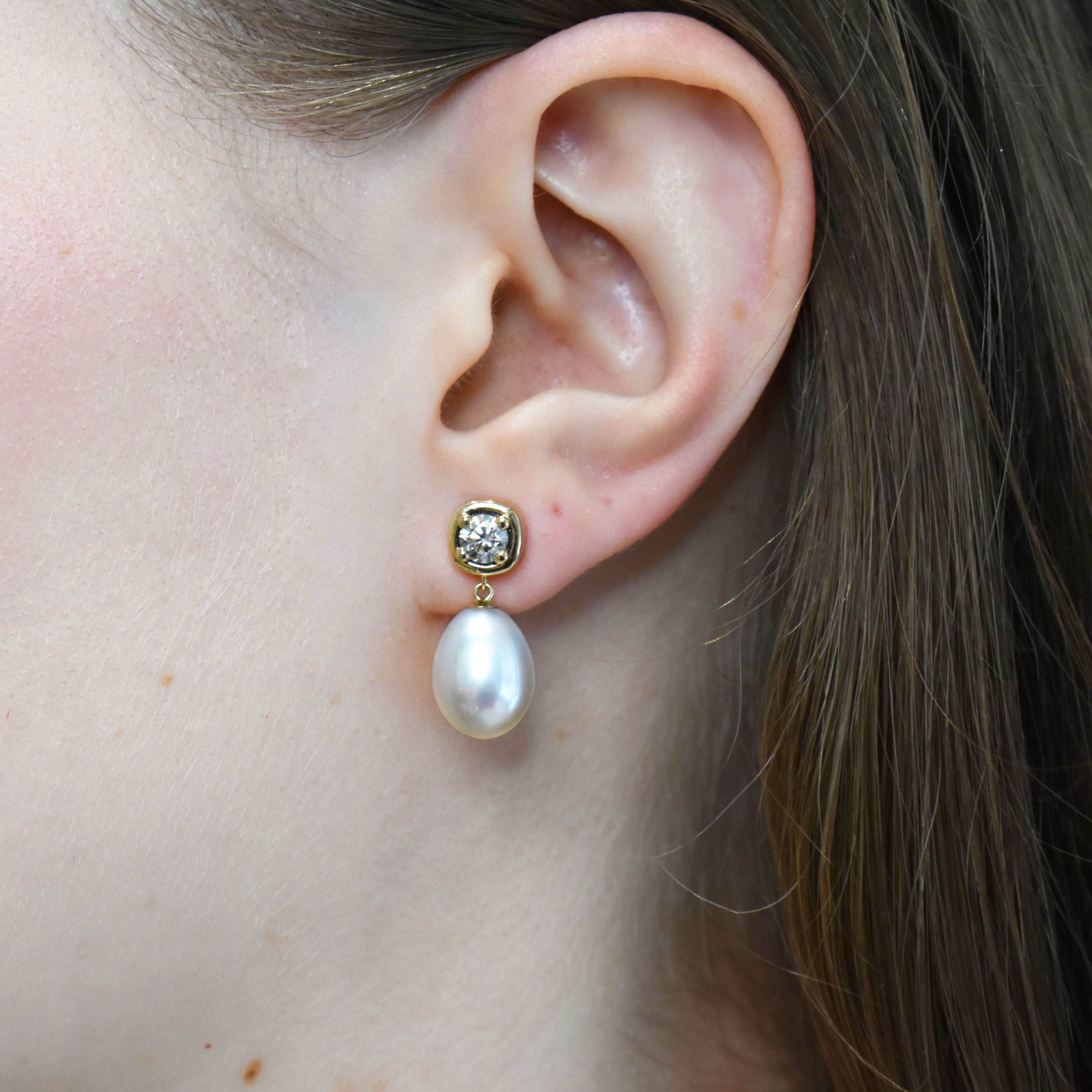 A drop earring with a .36ct round champagne diamond and fresh water pearl. Set in 14k yellow gold.