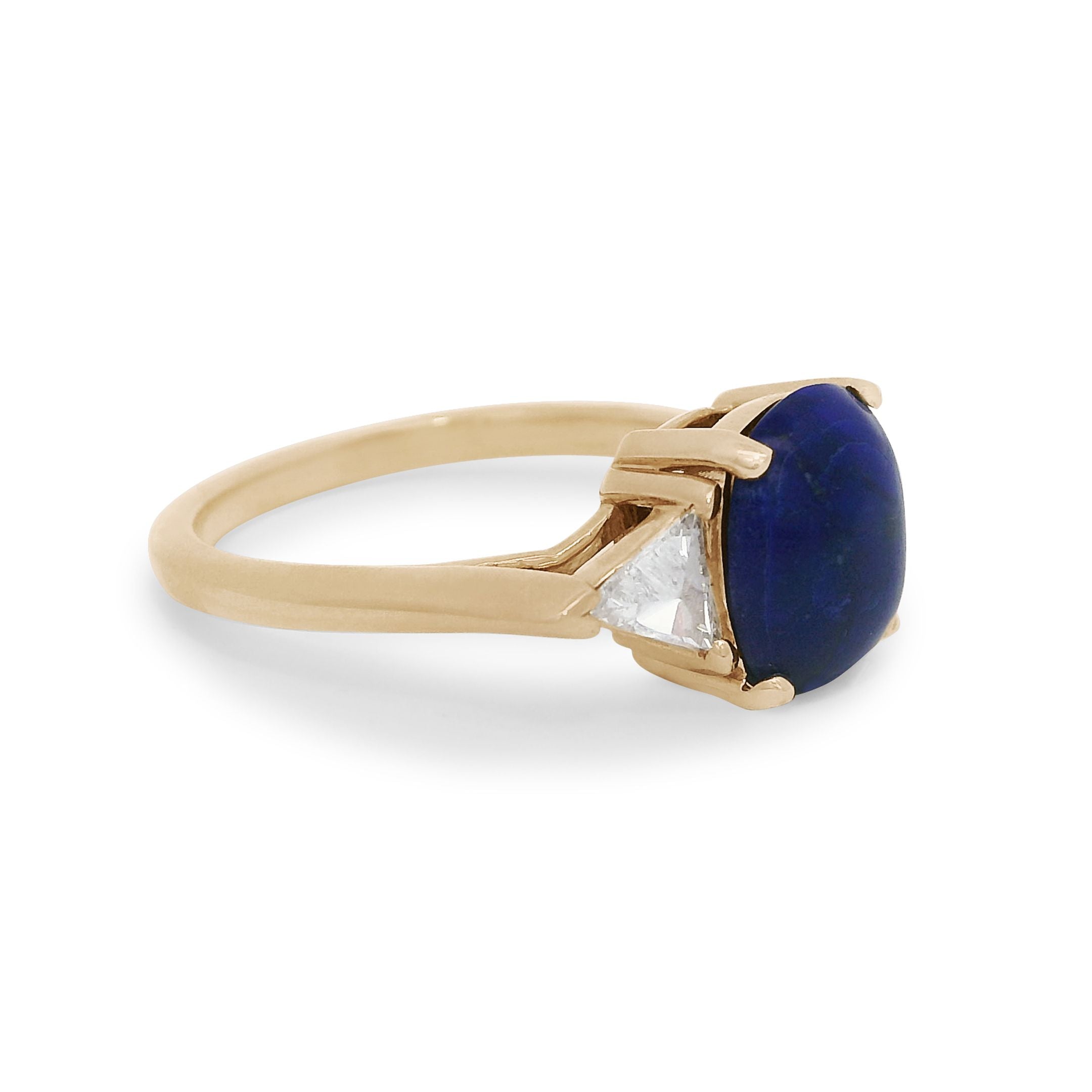 A lapis cabochon ring with white diamond trillion side stones set in 14k yellow gold. 