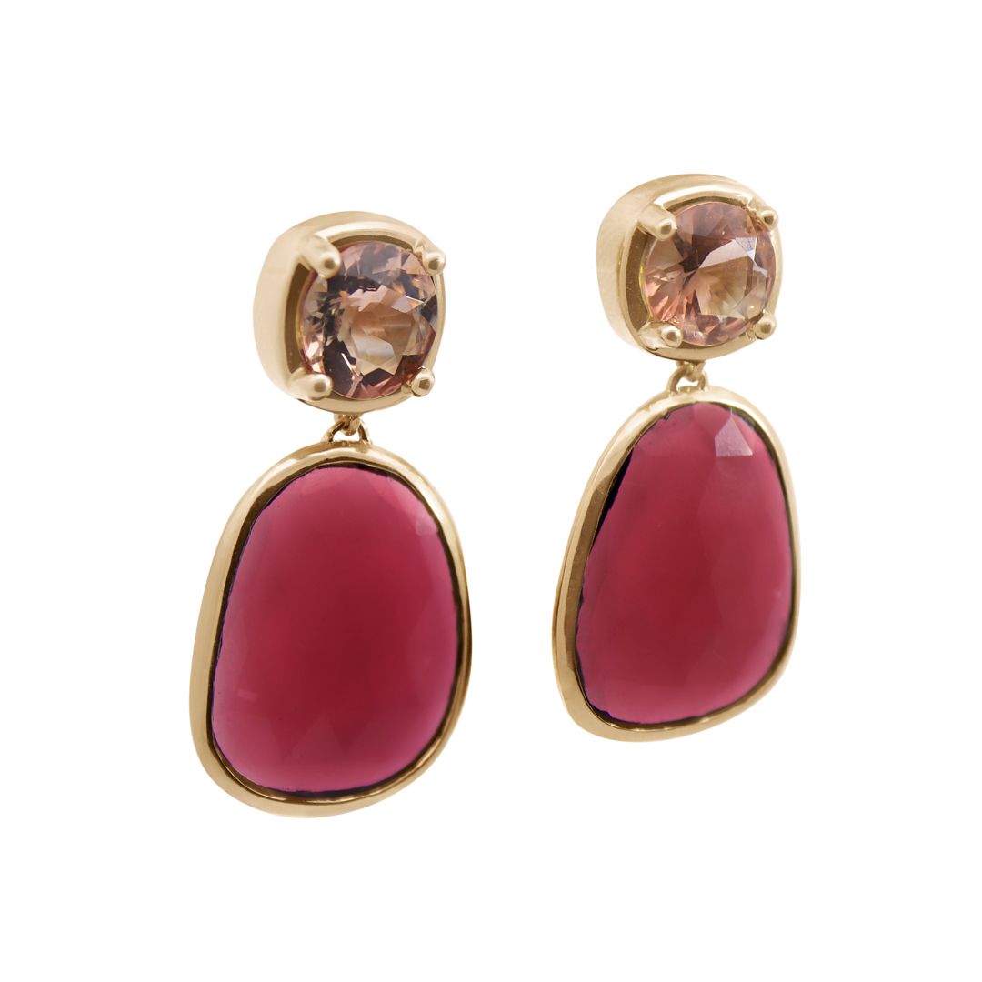 A pair of drop earrings featuring a cushion cut sunstone and a pink tourmaline slice set in yellow gold on a white background