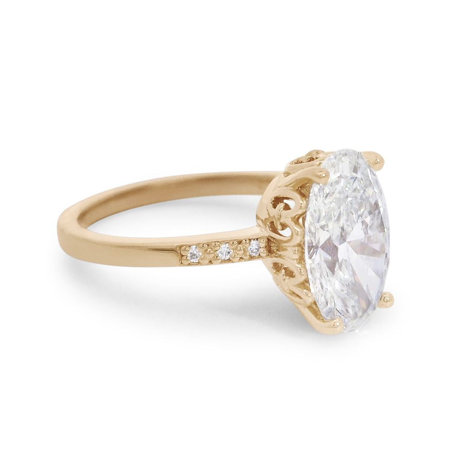 A 3/4 angle of a 2.11 ct white oval lab diamond engagement ring featuring pave diamonds on the band set in 14kt yellow gold.