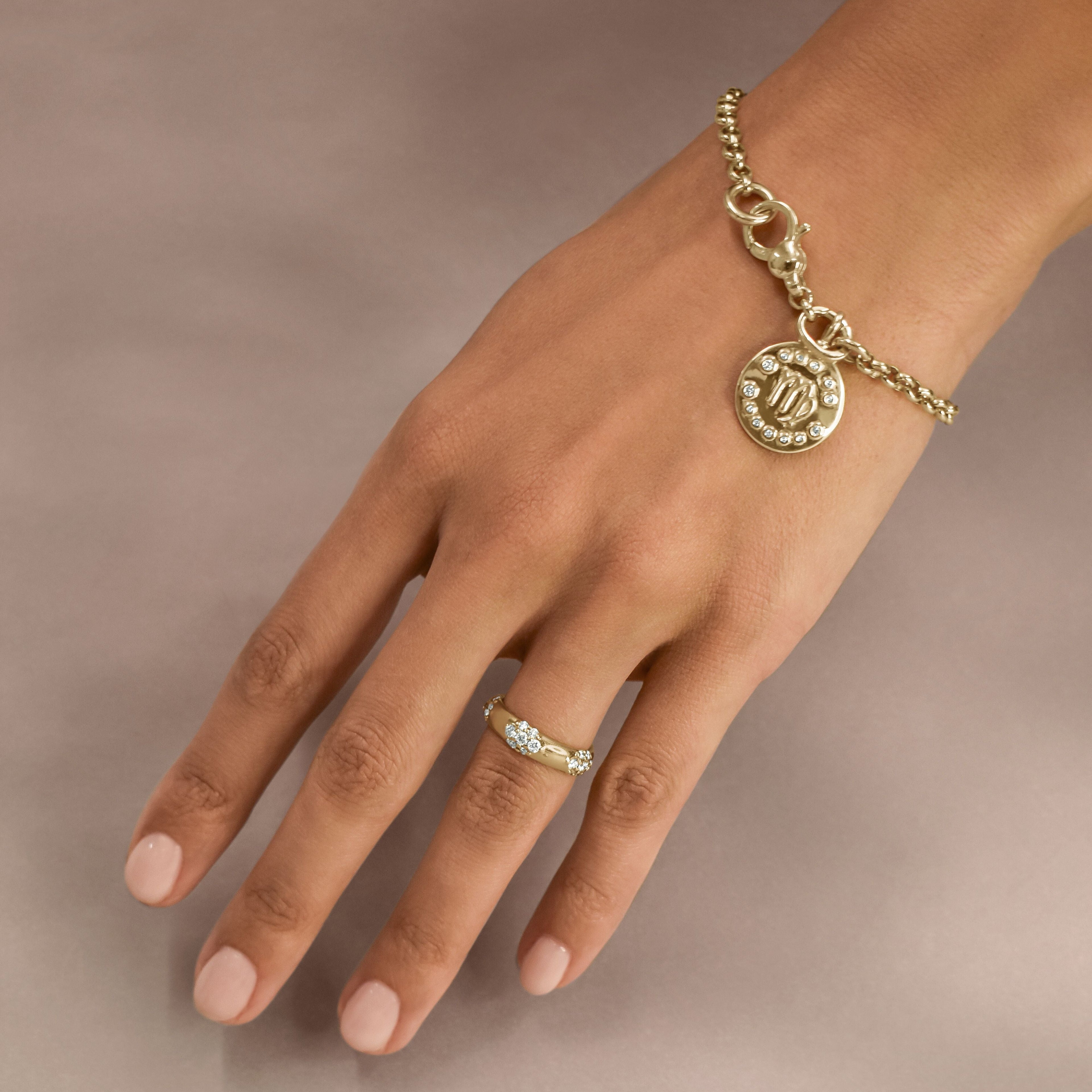 gold rolo chain bracelet with a gold zodiac charm on a hand. 