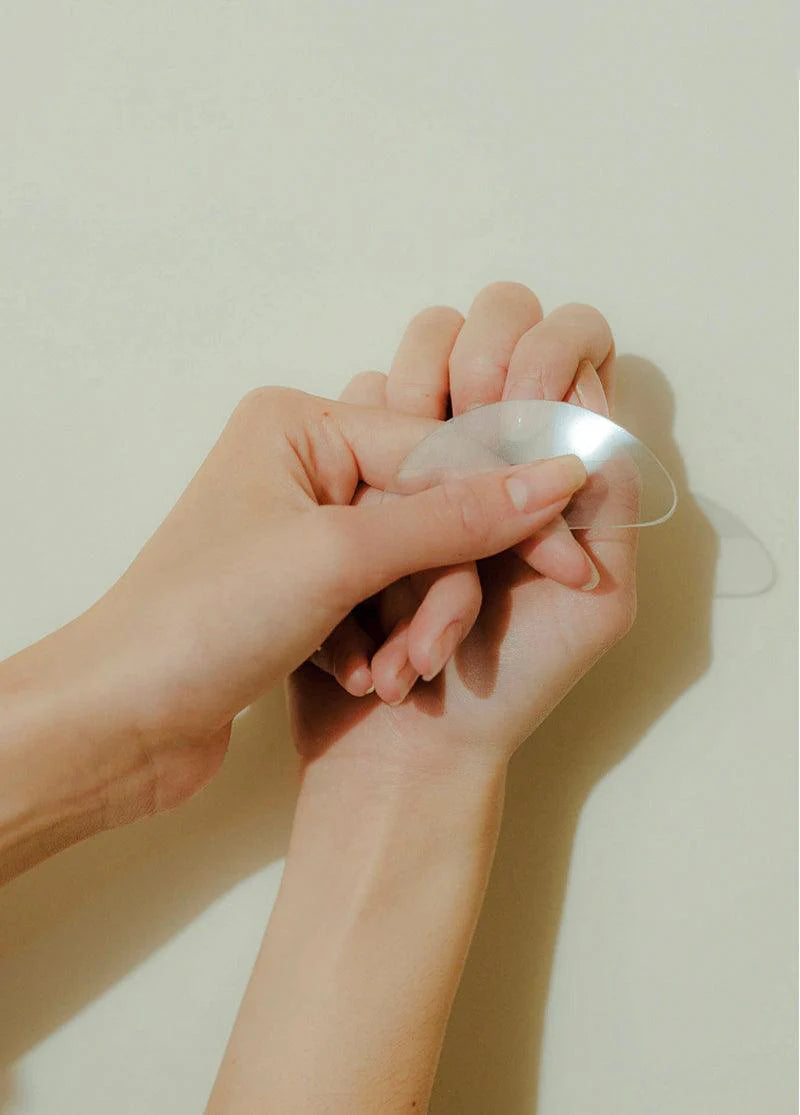 Hand holding a silver hair tie against a plain background
