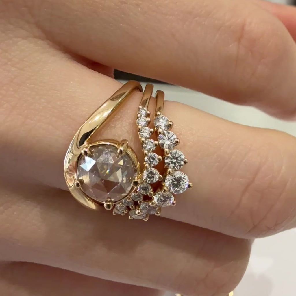 A close-up video of a finger with three rings, including a gold curve ring with a round champagne diamond, and two white diamond nesting bands
