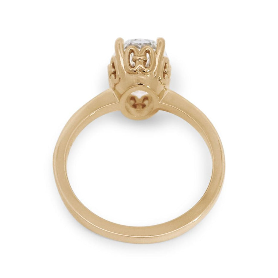 A high angle of a 2.11 ct white oval lab diamond engagement ring featuring pave diamonds on the band set in 14kt yellow gold.