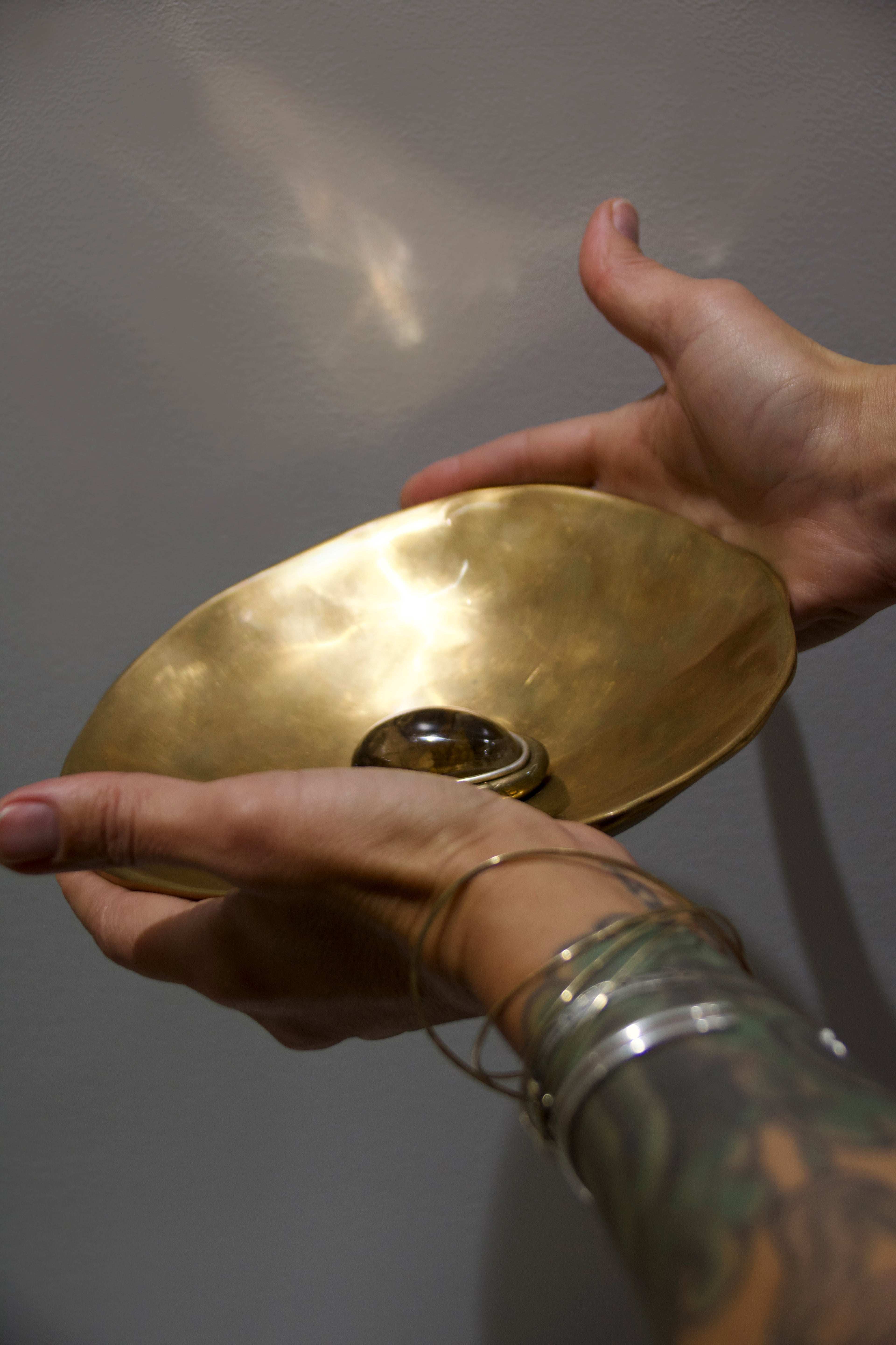 Person holding a gold object against a neutral background